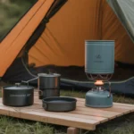 Essential camping accessories including a stove, cooking set, and tent in nature