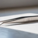 A pair of stainless steel tweezers on a white surface, showcasing their precision.